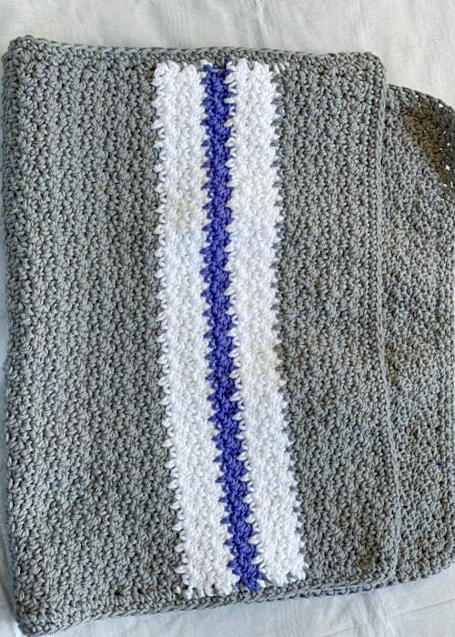 Folded in half grey crochet kitchen towel with stripes of white and gray to the ends