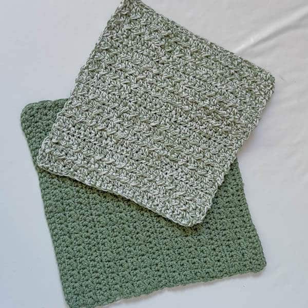 Two green crochet washcloth on a white surface