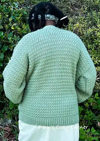 Handmade Orchid Crochet Cardigan displayed on a woman, featuring a lightweight open-front design made with worsted yarn in a soft green shade, shown in size M.