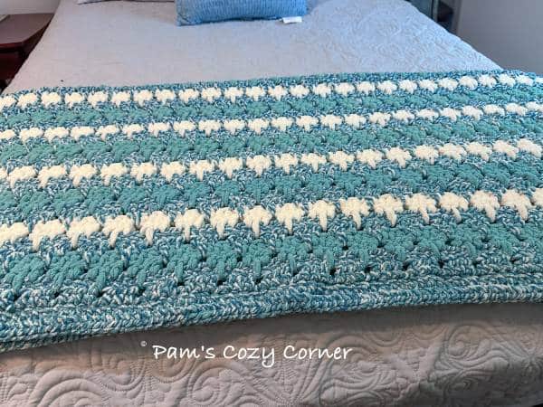 Chunky crochet blanket featuring teal and green colors with a soft vanilla contrast